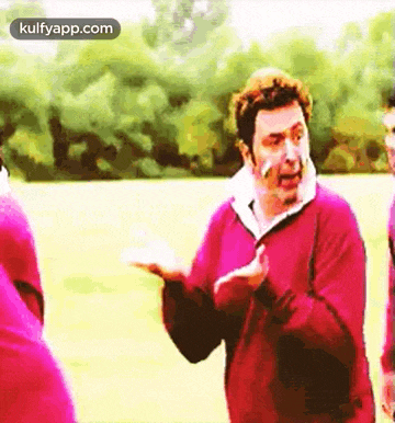 a man in a pink jacket is talking to another man .