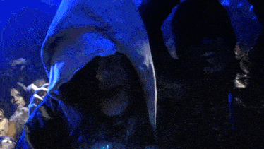 a woman in a hooded sweatshirt is smiling in front of a crowd of people