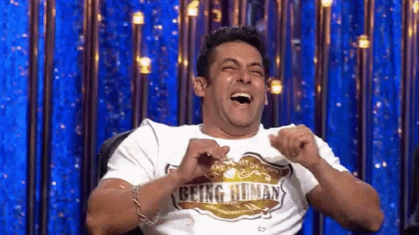 a man wearing a t-shirt that says being human is laughing with his mouth open .