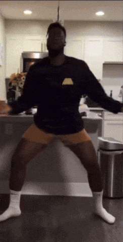 a man is dancing in a kitchen wearing a lakers sweatshirt