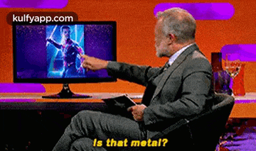 a man in a suit and tie is sitting in front of a computer screen and pointing at it .