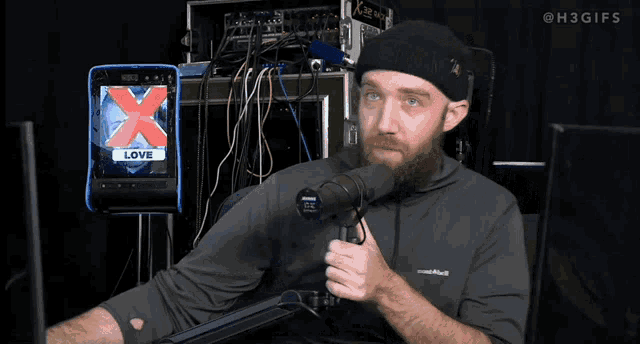 a man holds a microphone in front of a screen that says x love
