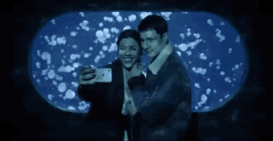 a man and woman take a selfie in front of an aquarium