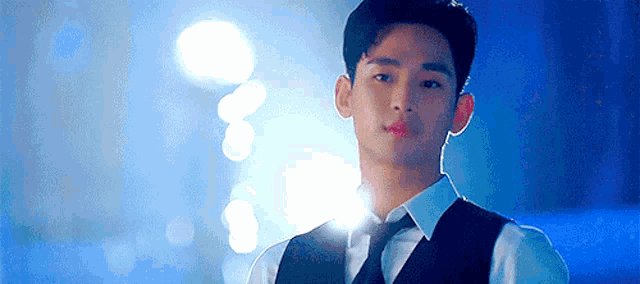 a young man in a suit and tie is standing in a dark room .