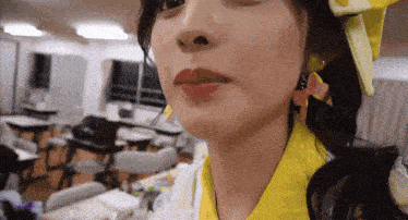 a close up of a woman 's face wearing a yellow shirt and earrings