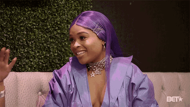 a woman with purple hair is smiling and wearing a bet logo