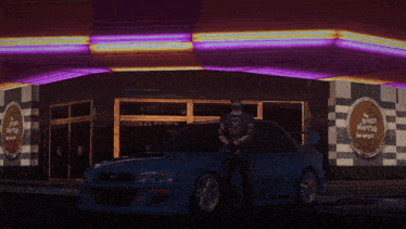 a man stands in front of a blue car in front of a building with a sign that says ' health wealth ' on it