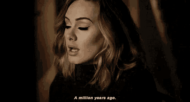 a woman is singing into a microphone in a dark room and says `` a million years ago '' .