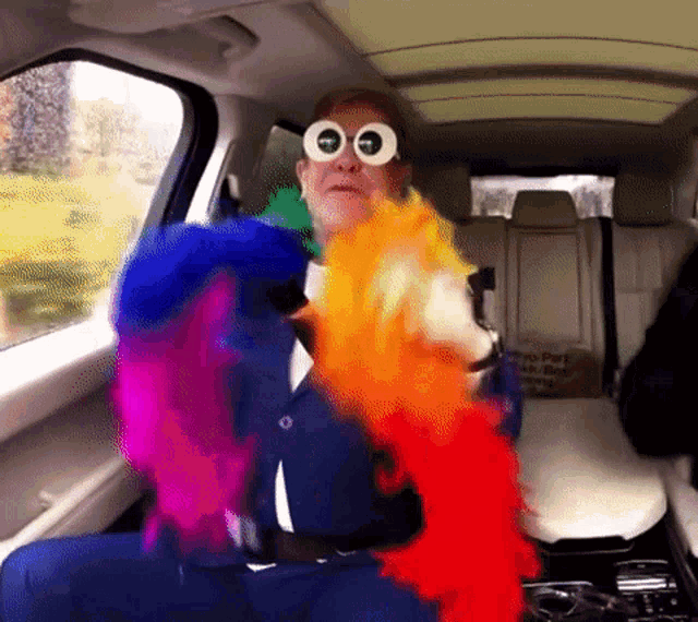 a man in a car wearing sunglasses and a rainbow boa