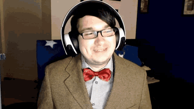 a man wearing headphones and a red bow tie smiles