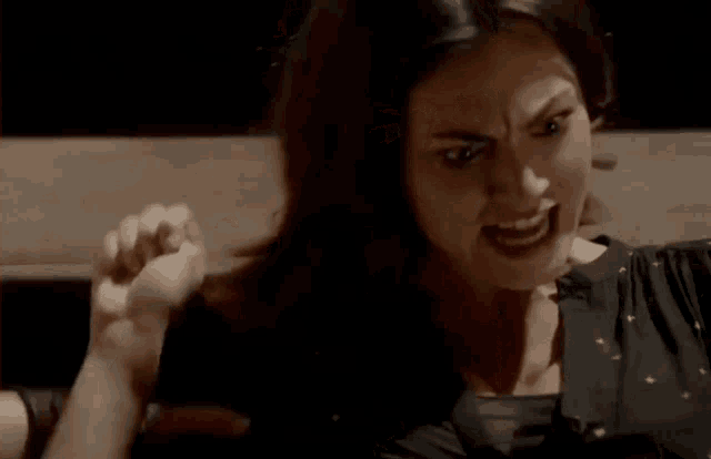 a close up of a woman making a funny face with her fist in the air .
