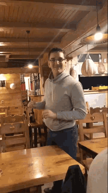 a man wearing glasses is standing in a restaurant holding a glass