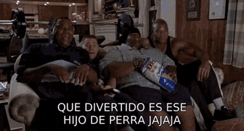 a group of men are sitting on a couch watching tv and one man is holding a bag of chips .