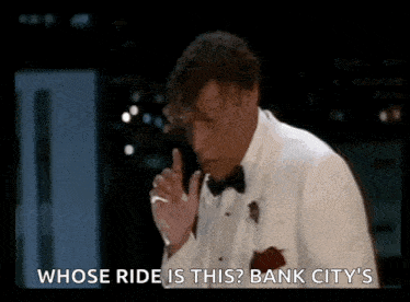 a man in a tuxedo is talking on a cell phone and says whose ride is this ? bank city 's .