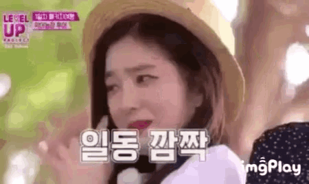 a girl wearing a straw hat is making a funny face while talking on a cell phone .