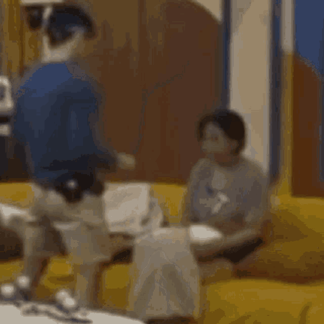 a man in a blue shirt is standing next to a woman on a yellow couch .