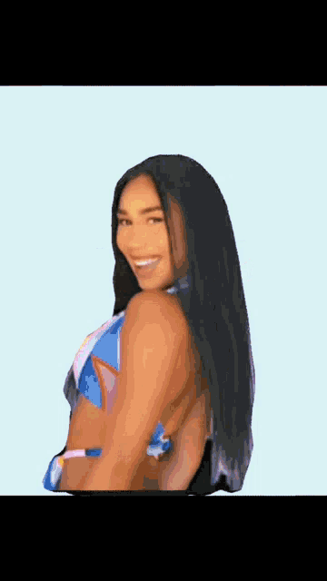 a woman in a bikini is smiling and looking over her shoulder at the camera .