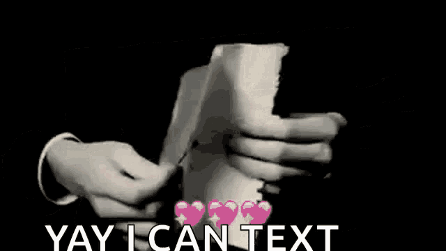 a person is holding a piece of paper with hearts on it and the words `` yay i can text '' .