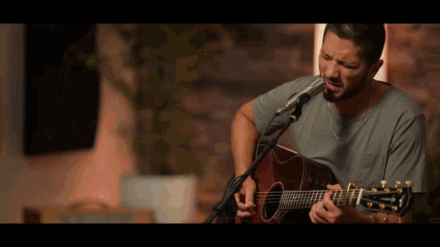 a man singing into a microphone while playing an acoustic guitar