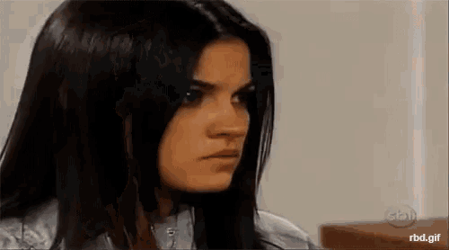 a woman with long black hair is making a serious face .