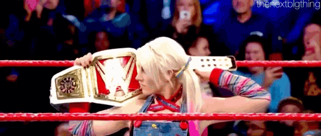 a woman in a wrestling ring is holding a championship belt