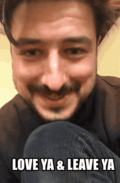 a man with a beard and mustache is smiling with the words love ya & leave ya below him