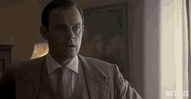 a man in a suit and tie stands in front of a netflix sign