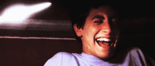 a man in a purple shirt is laughing with his mouth wide open