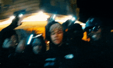 a group of people are standing next to each other in the dark holding guns .