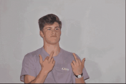 a man in a purple shirt is giving a thumbs up sign