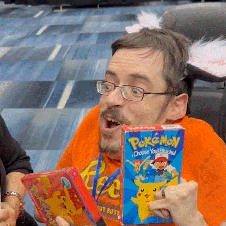 a man with glasses is holding a box of pokemon choose your pikachu .