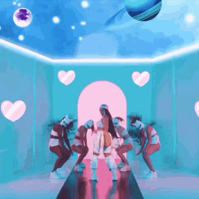 a group of women are dancing in a room with pink hearts on the walls