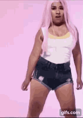 a woman in a pink wig and shorts is dancing .