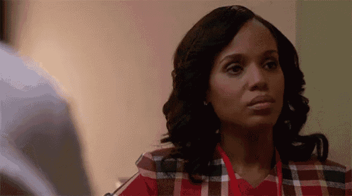 a woman wearing a plaid shirt and a red lanyard is looking at a man .