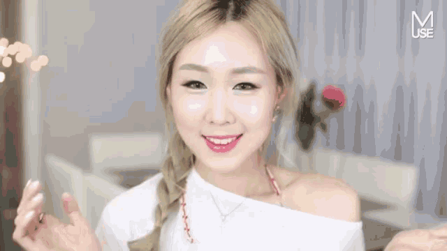 a woman wearing a white off the shoulder top is smiling with the letter m above her