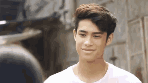 a young man in a white shirt is smiling and looking at another man .