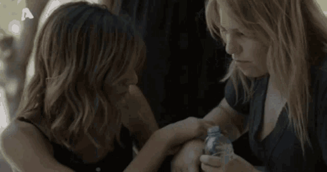 two women are hugging each other and one is holding a bottle of water