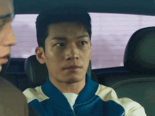 a man is sitting in the back seat of a car and looking at the camera .