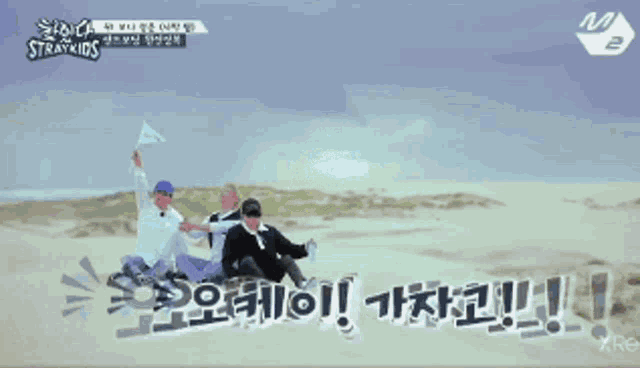 a group of people sitting on a sand dune with the word straykids written on the bottom