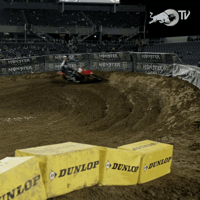 a person riding a dirt bike on a dirt track with dunlop boxes