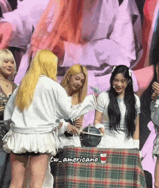 a group of women standing around a table with a cup that says tw_americano on the bottom