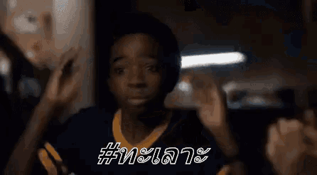 a young boy is making a funny face while wearing a blue and yellow jersey with the word # on it .