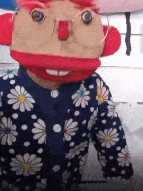 a puppet wearing glasses and a blue jacket with daisies