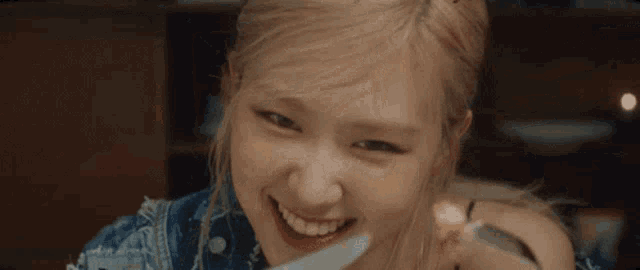 a woman in a denim jacket is eating a piece of food with a fork .