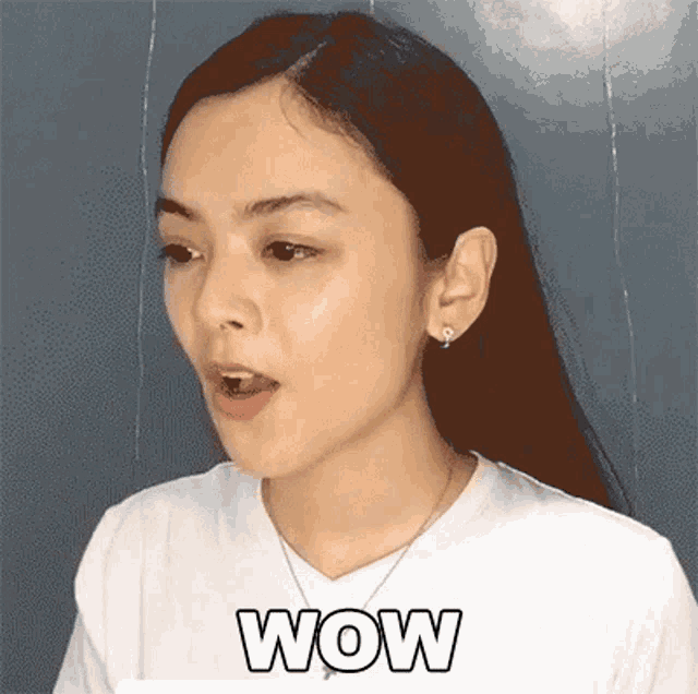 a woman in a white shirt is making a surprised face with the word wow above her