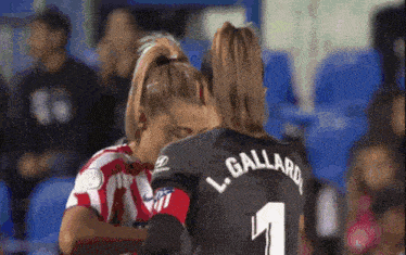 two female soccer players one of whom is wearing the number 1