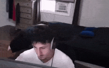 a man wearing headphones is sitting in a bedroom .