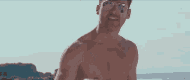 a shirtless man wearing sunglasses and a mustache is running on the beach