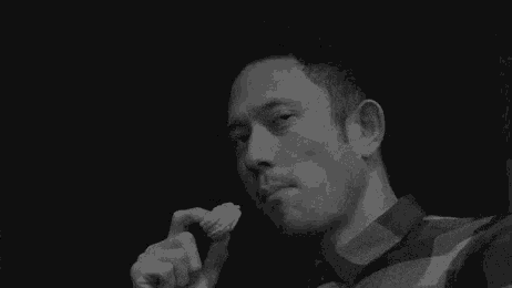 a black and white photo of a man eating a cookie .