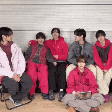 a group of young men are sitting next to each other on a couch .